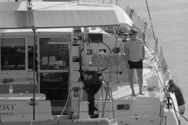 İtalya, Sicilya, Akdeniz, Marina di Ragusa (Ragusa Eyaleti); 8 Kasım 2023, limandaki katamaran yelkenli teknesinde bir kadın - EDITORIAL
