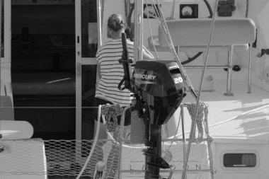 İtalya, Sicilya, Akdeniz, Marina di Ragusa (Ragusa Eyaleti); 8 Kasım 2023, limandaki katamaran yelkenli teknesinde bir kadın - EDITORIAL