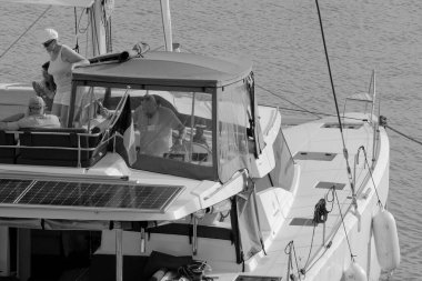 İtalya, Sicilya, Akdeniz, Marina di Ragusa (Ragusa Eyaleti); 9 Kasım 2023, limandaki katamaran yelkenli teknesindeki insanlar - EDITORIAL