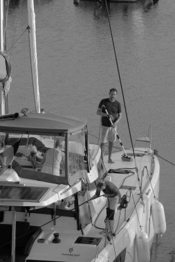 İtalya, Sicilya, Akdeniz, Marina di Ragusa (Ragusa Eyaleti); 9 Kasım 2023, limandaki katamaran yelkenli teknesindeki insanlar - EDITORIAL