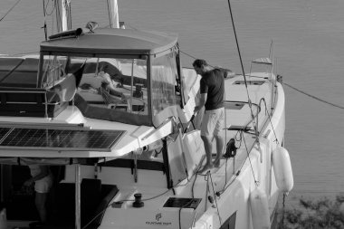 İtalya, Sicilya, Akdeniz, Marina di Ragusa (Ragusa Eyaleti); 9 Kasım 2023, limandaki bir katamaran yelkenli teknesinde adam - EDITORIAL