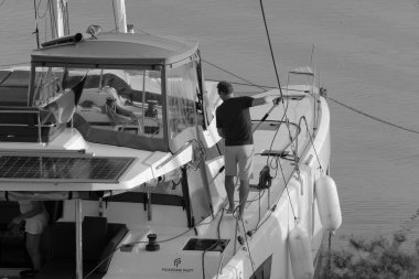 İtalya, Sicilya, Akdeniz, Marina di Ragusa (Ragusa Eyaleti); 9 Kasım 2023, limandaki bir katamaran yelkenli teknesinde adam - EDITORIAL