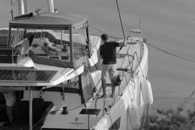 İtalya, Sicilya, Akdeniz, Marina di Ragusa (Ragusa Eyaleti); 9 Kasım 2023, limandaki bir katamaran yelkenli teknesinde adam - EDITORIAL