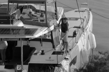 İtalya, Sicilya, Akdeniz, Marina di Ragusa (Ragusa Eyaleti); 9 Kasım 2023, limandaki bir katamaran yelkenli teknesinde adam - EDITORIAL