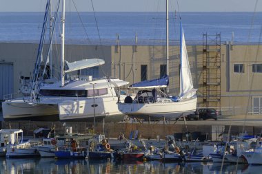 İtalya, Sicilya, Marina di Ragusa (Ragusa Eyaleti); 16 Kasım 2023, yerel balıkçı tekneleri ve limanda bir yelkenli teknesi - EDITORIAL