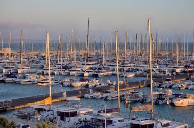 İtalya, Sicilya, Akdeniz, Marina di Ragusa; 17 Kasım 2023, gün batımında limanda motorlu tekne ve lüks yatlar