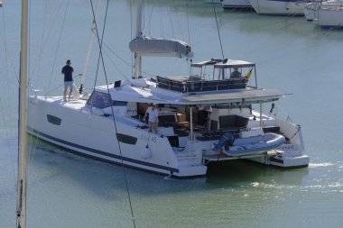 İtalya, Sicilya, Akdeniz, Marina di Ragusa (Ragusa Eyaleti); 19 Kasım 2023, limandaki bir katamaran yelkenli teknesinde erkekler - EDITORIAL