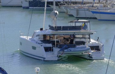 İtalya, Sicilya, Akdeniz, Marina di Ragusa (Ragusa Eyaleti); 19 Kasım 2023, limandaki bir katamaran yelkenli teknesinde erkekler - EDITORIAL