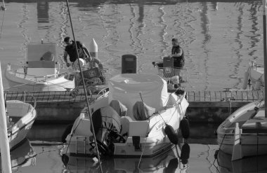 İtalya, Sicilya, Akdeniz, Marina di Ragusa (Ragusa ili); 30 Kasım 2023, limandaki insanlar, motorlu tekneler ve lüks yatlar - EDITORIAL