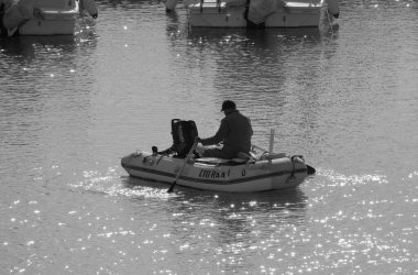 İtalya, Sicilya, Akdeniz, Marina di Ragusa (Ragusa Eyaleti); 23 Aralık 2023, limandaki bir lastik teknede adam - EDITORIAL