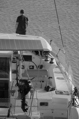 İtalya, Sicilya, Akdeniz, Marina di Ragusa (Ragusa Eyaleti); 23 Aralık 2023, limandaki bir katamaran yelkenli teknesinde adam - EDITORIAL