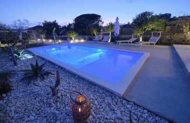 İtalya, Sicilya, Ragusa Eyaleti, kırsal kesim; 30 Mart 2023, zarif özel ev, yüzme havuzu manzarası ve gün batımında bahçe - EDITORIAL