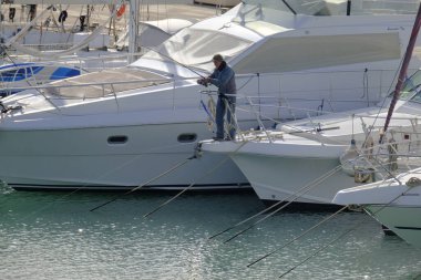 İtalya, Sicilya, Akdeniz, Marina di Ragusa (Ragusa Eyaleti); 20 Ocak 2024, limanda lüks bir yatta balıkçı - EDITORIAL