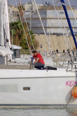 İtalya, Sicilya, Akdeniz, Marina di Ragusa (Ragusa Eyaleti); 20 Ocak 2024, limandaki bir katamaran yelkenli teknesinde adam - EDITORIAL