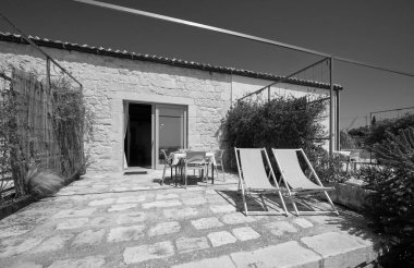 İtalya, Sicilya, Ragusa Eyaleti, kırsal kesim; 13 Nisan 2023, zarif bir çiftlik merkezi, yemek masası olan taş döşeli verandanın manzarası - EDITORIAL