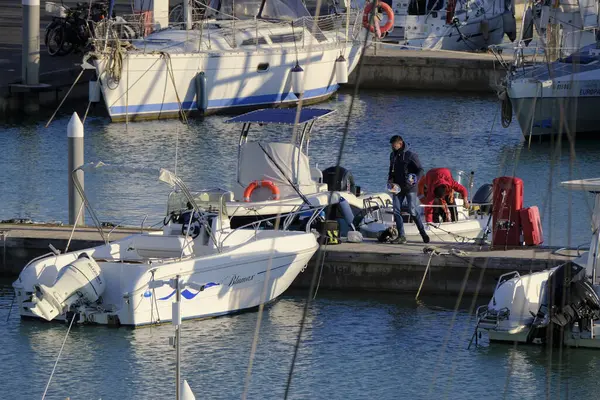 İtalya, Sicilya, Akdeniz, Marina di Ragusa (Ragusa Eyaleti); 3 Şubat 2024, limandaki bir motorlu teknede balıkçı - EDITORIAL