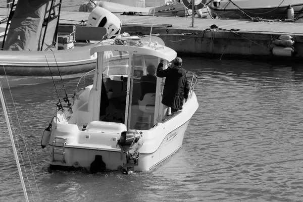 İtalya, Sicilya, Akdeniz, Marina di Ragusa (Ragusa Eyaleti); 22 Şubat 2024, limandaki bir motorlu teknede balıkçı - EDITORIAL