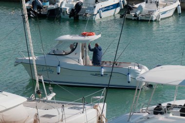 İtalya, Sicilya, Akdeniz, Marina di Ragusa (Ragusa Eyaleti); 22 Şubat 2024, limandaki bir motorlu teknede balıkçı - EDITORIAL