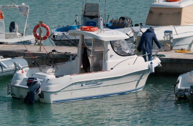 İtalya, Sicilya, Akdeniz, Marina di Ragusa (Ragusa Eyaleti); 22 Şubat 2024, limandaki bir motorlu teknede balıkçı - EDITORIAL