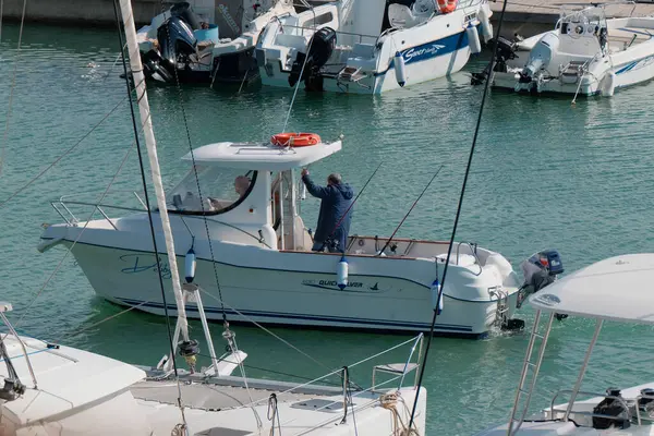 İtalya, Sicilya, Akdeniz, Marina di Ragusa (Ragusa Eyaleti); 22 Şubat 2024, limandaki bir motorlu teknede balıkçı - EDITORIAL