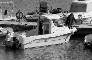 İtalya, Sicilya, Akdeniz, Marina di Ragusa (Ragusa Eyaleti); 22 Şubat 2024, limandaki bir motorlu teknede balıkçı - EDITORIAL