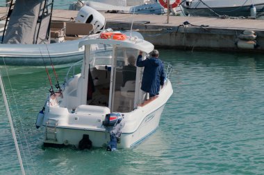 İtalya, Sicilya, Akdeniz, Marina di Ragusa (Ragusa Eyaleti); 22 Şubat 2024, limandaki bir motorlu teknede balıkçı - EDITORIAL