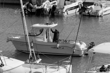 İtalya, Sicilya, Akdeniz, Marina di Ragusa (Ragusa Eyaleti); 22 Şubat 2024, limandaki bir motorlu teknede balıkçı - EDITORIAL