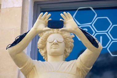 Italy, Sicily, Scicli (Ragusa province), statue of a photographer taking pictures on a balcony in a central street of the town clipart