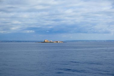 İtalya, Sicilya, Akdeniz, Egadi takımadası, Favignana Adası (Trapani Eyaleti); arka planda iki Formiche kayasından biri ve Sicilya kıyısı manzarası 