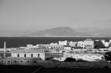 İtalya, Sicilya, Akdeniz, Egadi takımadaları, Favignana Adası (Trapani Eyaleti); liman, Florio Sarayı ve arka plandaki eski orkinos balıkçılık fabrikası çatıları (Trapani ve Sicilya kıyıları) manzarası)