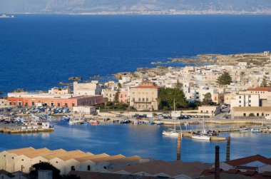 İtalya, Sicilya, Akdeniz, Egadi takımadaları, Favignana Adası (Trapani Eyaleti); liman, Florio Sarayı ve arka plandaki eski orkinos balıkçılık fabrikası çatıları (Trapani ve Sicilya kıyıları) manzarası)