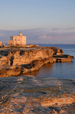 Itali, sicily, mediterranean sea, Egadi archipelago, Favignana island (Trapani Province); view of a lighthouse and the rocky coast of the island at sunset clipart