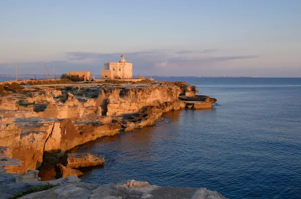 İtalya, Sicilya, Akdeniz, Egadi takımadaları, Favignana Adası (Trapani Eyaleti); gün batımında bir deniz feneri ve adanın kayalık sahili manzarası
