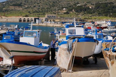 İtalya, Sicilya, Akdeniz, Egadi takımadaları, Favignana Adası (Trapani Eyaleti); limanda insanlar ve balıkçı tekneleri (arka plandaki eski ton balığı fabrikası))