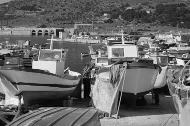 İtalya, Sicilya, Akdeniz, Egadi takımadaları, Favignana Adası (Trapani Eyaleti); limanda insanlar ve balıkçı tekneleri (arka plandaki eski ton balığı fabrikası))