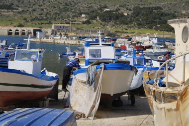 İtalya, Sicilya, Akdeniz, Egadi takımadaları, Favignana Adası (Trapani Eyaleti); limanda insanlar ve balıkçı tekneleri (arka plandaki eski ton balığı fabrikası))