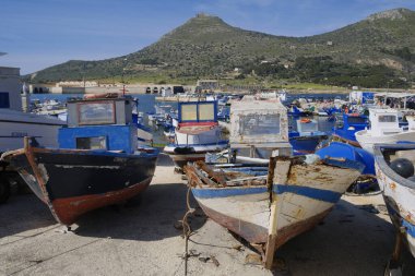 İtalya, Sicilya, Akdeniz, Egadi takımadaları, Favignana Adası (Trapani Eyaleti); 21 Mart 2024, limanda ahşap balıkçı tekneleri (arka planda eski ton balığı fabrikası) -