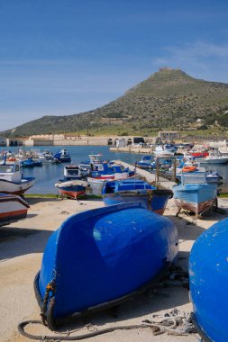İtalya, Sicilya, Akdeniz, Egadi takımadaları, Favignana Adası (Trapani Eyaleti); 21 Mart 2024, limanda ahşap balıkçı tekneleri (arka planda eski ton balığı fabrikası) -