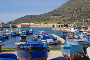 İtalya, Sicilya, Akdeniz, Egadi takımadaları, Favignana Adası (Trapani Eyaleti); 21 Mart 2024, limanda ahşap balıkçı tekneleri (arka planda eski ton balığı fabrikası) -