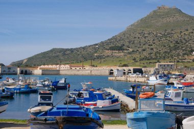 İtalya, Sicilya, Akdeniz, Egadi takımadaları, Favignana Adası (Trapani Eyaleti); 21 Mart 2024, limanda ahşap balıkçı tekneleri (arka planda eski ton balığı fabrikası) -