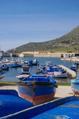 İtalya, Sicilya, Akdeniz, Egadi takımadaları, Favignana Adası (Trapani Eyaleti); 21 Mart 2024, limanda ahşap balıkçı tekneleri (arka planda eski ton balığı fabrikası) -