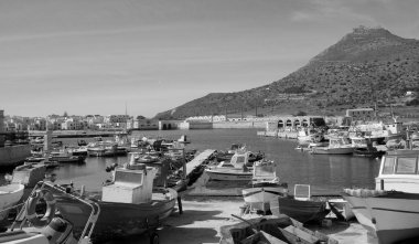 İtalya, Sicilya, Akdeniz, Egadi takımadaları, Favignana Adası (Trapani Eyaleti); 21 Mart 2024, limanda ahşap balıkçı tekneleri (arka planda eski ton balığı fabrikası) -