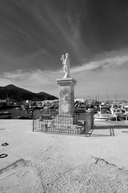 İtalya, Sicilya, Akdeniz, Egadi takımadaları, Favignana Adası (Trapani Eyaleti); limandaki Madonna heykeli ve balıkçı tekneleri manzarası 