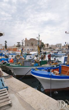 İtalya, Sicilya, Akdeniz, Egadi takımadaları, Favignana Adası (Trapani Eyaleti); 22 Mart 2024, balıkçılar, balıkçılar, balıkçı tekneleri ve ağlar limanda (arkada Florio Sarayı) - EDITORIAL