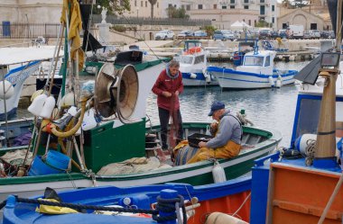 İtalya, Sicilya, Akdeniz, Egadi takımadaları, Favignana Adası (Trapani Eyaleti); 22 Mart 2024, limanda balıkçılar, balıkçılar, balıkçı tekneleri ve ağlar - EDITORIAL