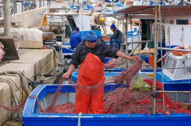 İtalya, Sicilya, Akdeniz, Egadi takımadaları, Favignana Adası (Trapani Eyaleti); 22 Mart 2024, limanda balıkçılar, balıkçılar, balıkçı tekneleri ve ağlar - EDITORIAL