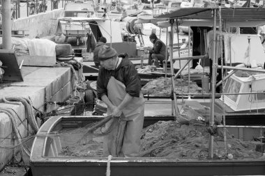 İtalya, Sicilya, Akdeniz, Egadi takımadaları, Favignana Adası (Trapani Eyaleti); 22 Mart 2024, limanda balıkçılar, balıkçılar, balıkçı tekneleri ve ağlar - EDITORIAL