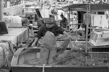 İtalya, Sicilya, Akdeniz, Egadi takımadaları, Favignana Adası (Trapani Eyaleti); 22 Mart 2024, limanda balıkçılar, balıkçılar, balıkçı tekneleri ve ağlar - EDITORIAL