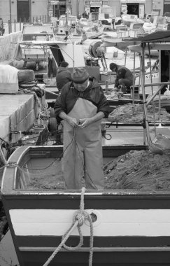 İtalya, Sicilya, Akdeniz, Egadi takımadaları, Favignana Adası (Trapani Eyaleti); 22 Mart 2024, limanda balıkçılar, balıkçılar, balıkçı tekneleri ve ağlar - EDITORIAL