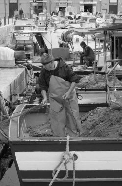 İtalya, Sicilya, Akdeniz, Egadi takımadaları, Favignana Adası (Trapani Eyaleti); 22 Mart 2024, limanda balıkçılar, balıkçılar, balıkçı tekneleri ve ağlar - EDITORIAL